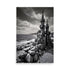 Dramatic monochrome coastal scene showcases nature's power. Rugged boulders lead to ornate stone tower against turbulent sky. Intricate spires contrast crashing waves, ominous clouds. Timeless architectural presence endures elemental forces.